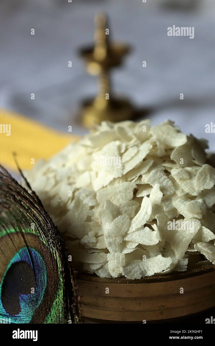 Nahaufnahme von rohem Poha/geschlagenem Reis/abgeflachtem Reis/Messingöllampe/Pfauenfeder-Krishna Janmashtami Stockfoto