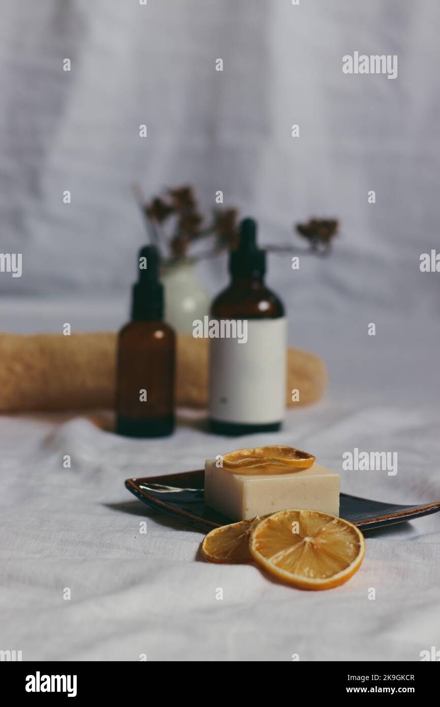 Ätherische Ölflaschen und vegane Bio-Seife mit getrockneten Zitronenscheiben, um das Konzept von Spa, Schönheit und Wellness zu zeigen Stockfoto
