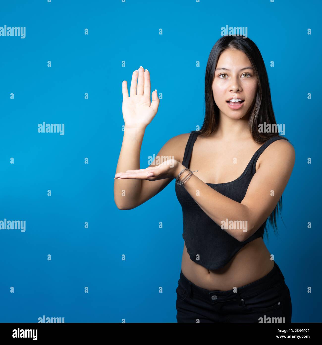 Junge trendige, überraschte Frau, die auf blauem Hintergrund einen Kopierplatz auf ihrer Handfläche hält und vorstellt Stockfoto