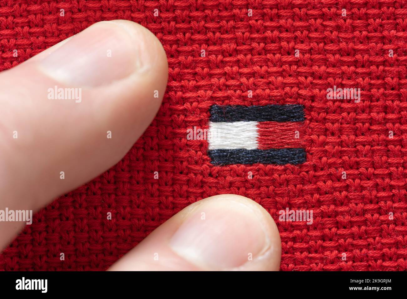 Finger berühren das Tommy Hilfiger Logo auf einem Sweatshirt. Thema: Modemarke, Männermode, Herrenbekleidung, Luxuskleidung, Modehaus Stockfoto