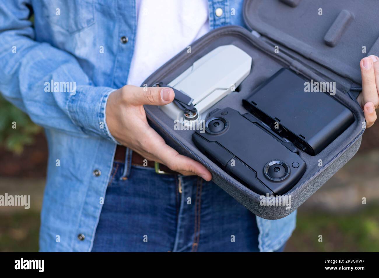 Nahaufnahme einer kleinen tragbaren und faltbaren grauen Drohne mit einer kamera von 4K, die in den Händen eines jungen Mannes gehalten wird Stockfoto