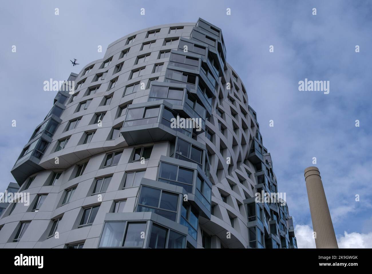 Nahaufnahme des Prospect Place, eines neuen Gebäudes am Battersea Power Station Development, mit einem ikonischen Kamin auf der rechten Seite und einem Flugzeug auf der linken Seite. Stockfoto