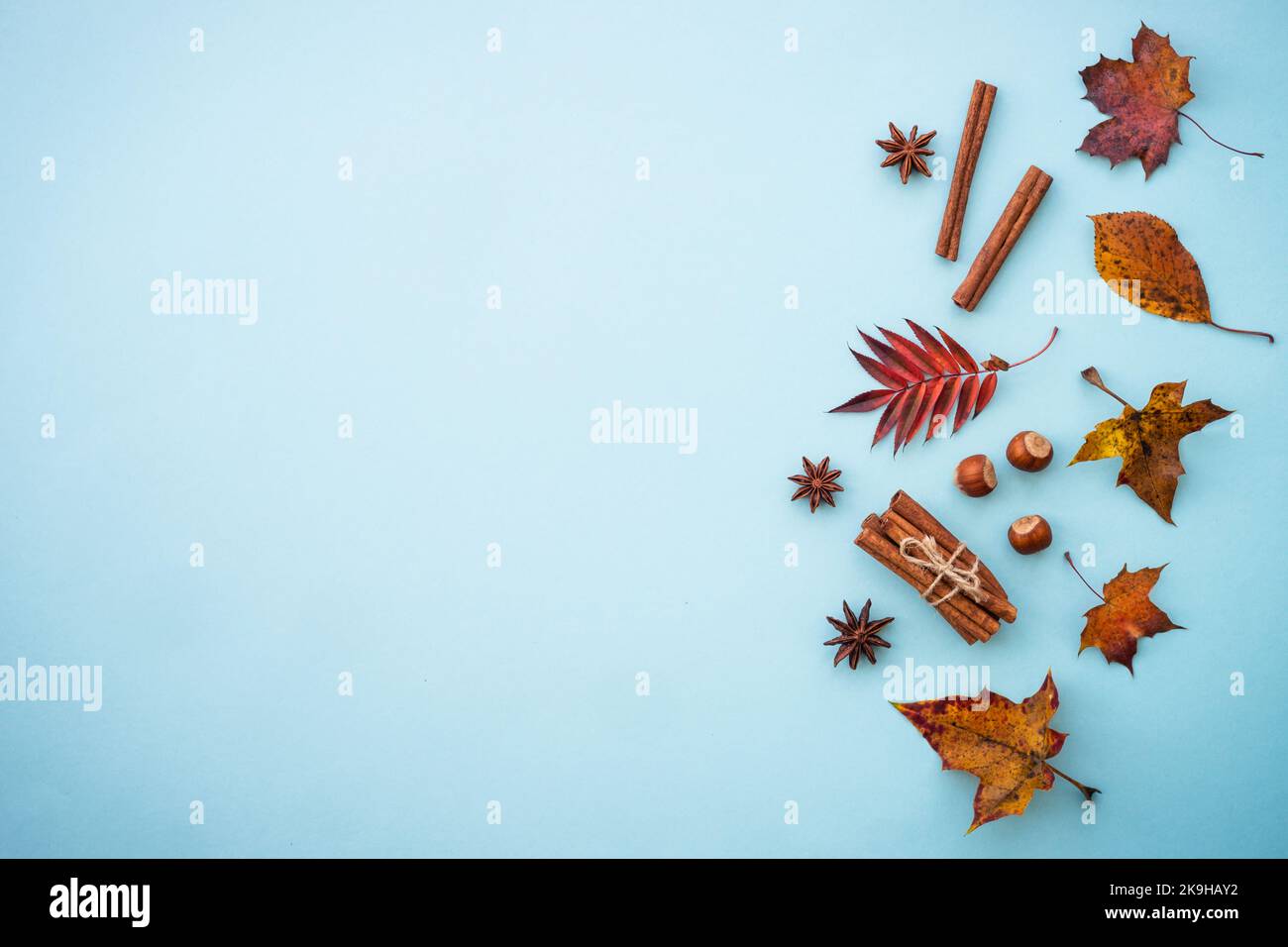 Kreative Komposition mit Herbstblättern, Gewürzen und Nüssen auf Blau. Stockfoto