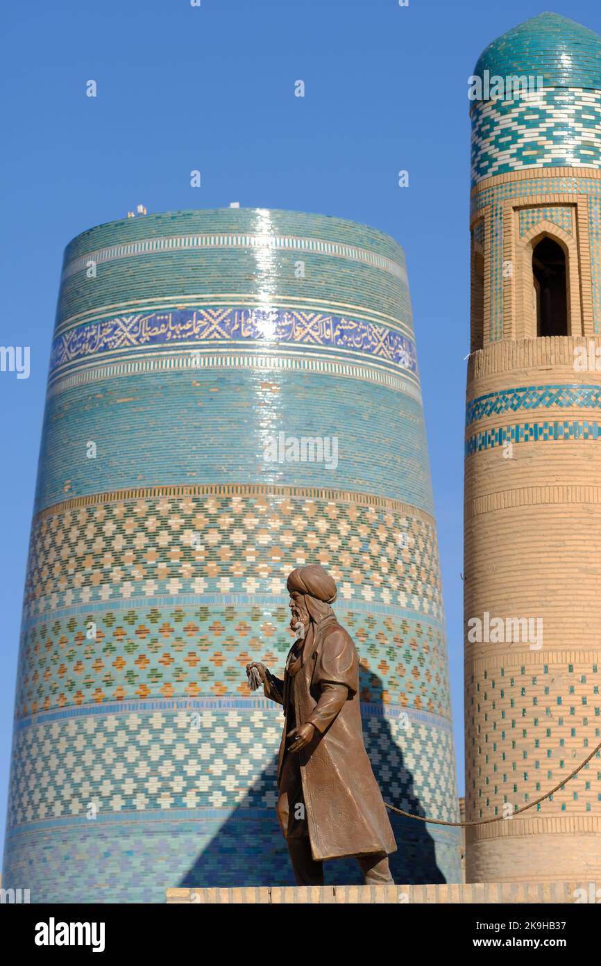 Chiwa Usbekistan - Antike Handelsfigur Denkmal der alten Seidenstraßen auf der UNESCO-Stätte IInchon Qala mit dem Minarett von Kalta im Hintergrund Stockfoto