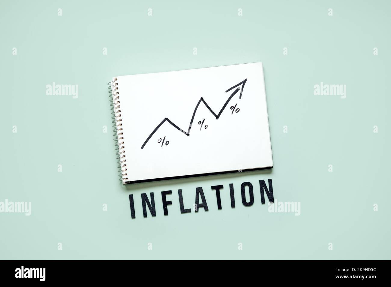 Konzept der Inflation in der Finanzkrise. Aufwachsen schwarzer Pfeil auf offenem Notizblock und Wortinflation auf blauem Hintergrund. Steigende Lebenshaltungskosten. Stockfoto