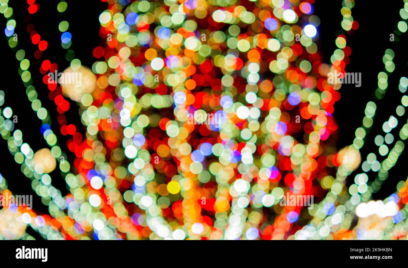 Weihnachtsbaum des neuen Jahres, geschmückt mit leuchtenden bunten Girlanden und Beleuchtung in der Nacht. Weihnachtsbaum mit blinkenden Lichtern. Unscharfer Hintergrund. Neujahr Weihnachtsferien. Stockfoto