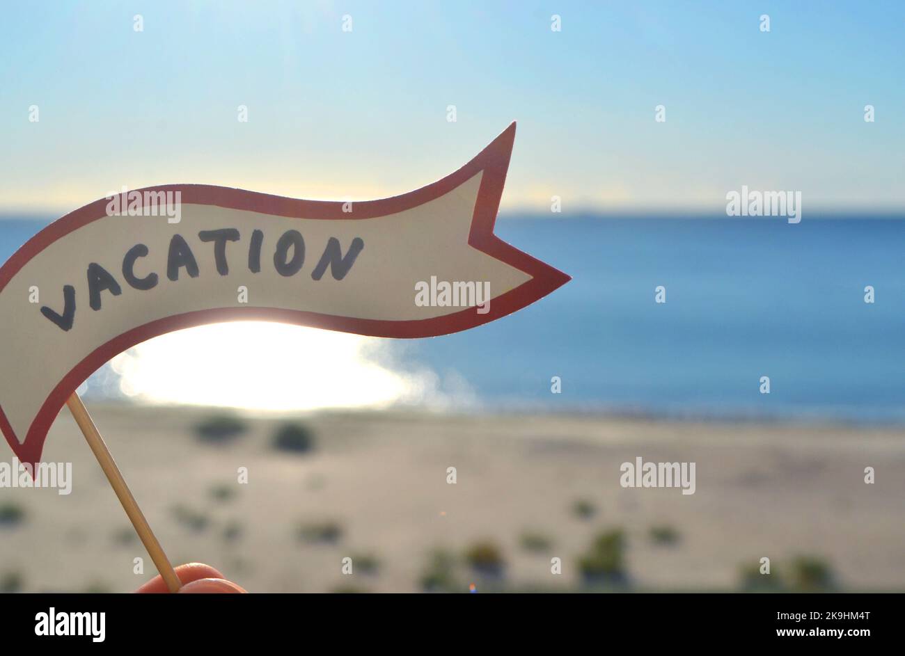 Halten Sie sich an Papier Sprechblase mit Worten Urlaub auf dem Hintergrund Meer, Himmel, Sandstrand an einem sonnigen Sommertag. Text-Ballons mit Text aus Buchstaben. Konzept, Symbol, Zeichen Urlaub Reise Tourismus Rest. Stockfoto