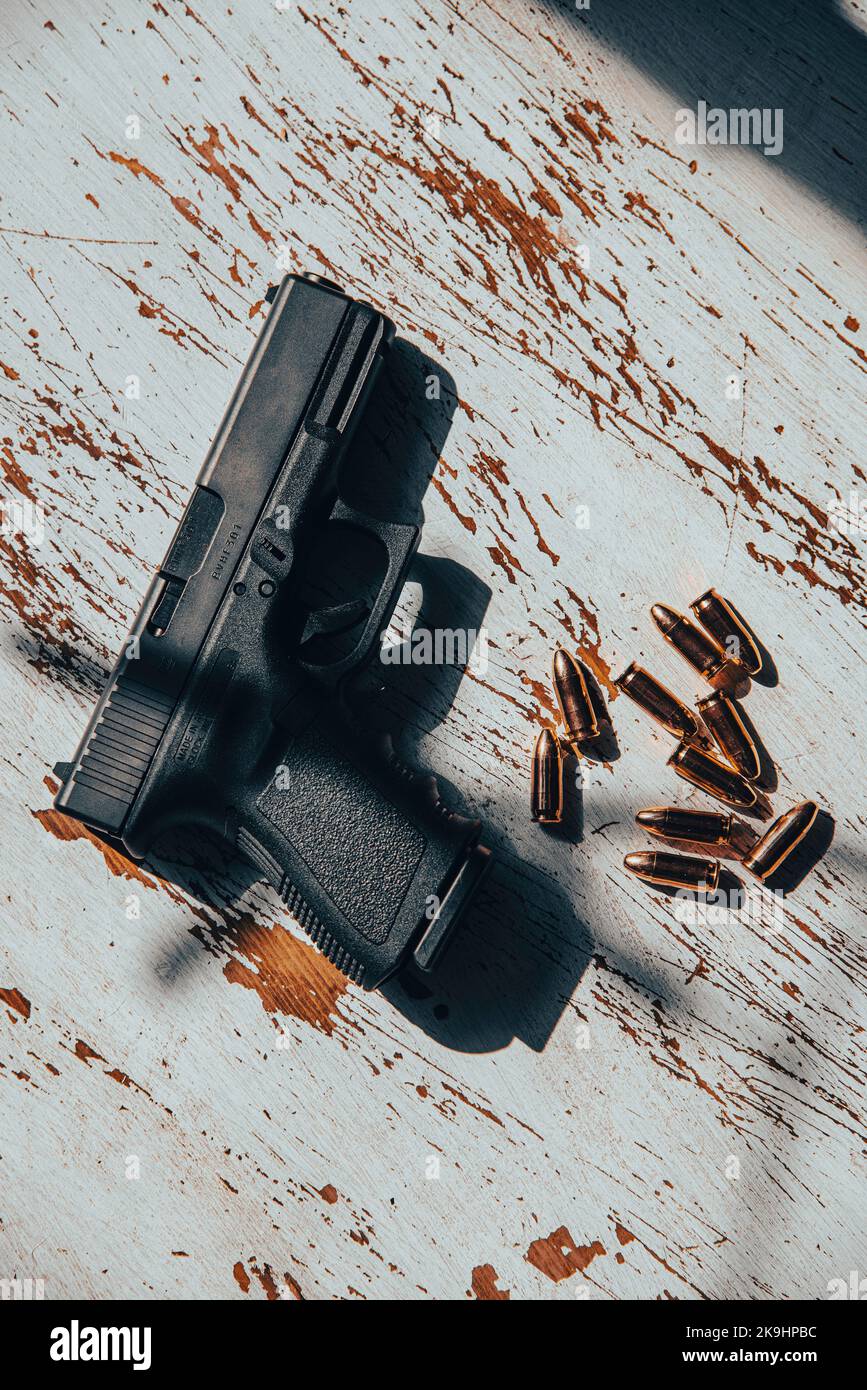 Eine halbautomatische Pistole aus Österreich, Glock aus dem Jahr 9mm, die auf einem Holztisch sitzt, zusammen mit 9mm Kugeln. Stockfoto