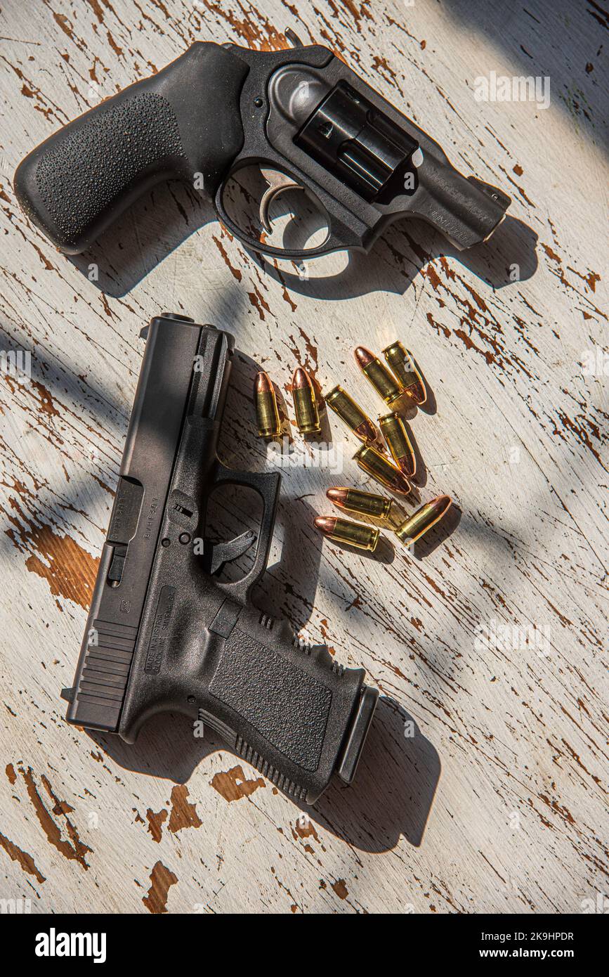 Eine schwarze Glock 19, 9mm, eine Pistole und eine Ruger, 9mm, stumpfe Nase, einen Revolver auf einem Holztisch, zusammen mit ein paar Kugeln. Stockfoto