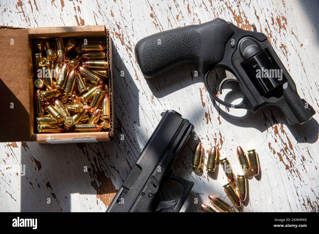 Eine schwarze Glock 19, 9mm, eine Pistole und eine Ruger, 9mm, stumpfe Nase, einen Revolver auf einem Holztisch, zusammen mit ein paar Kugeln. Stockfoto