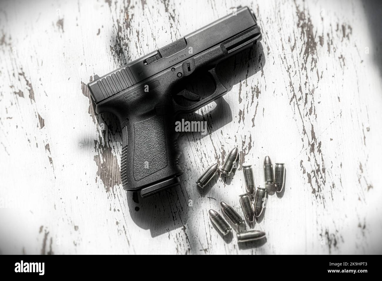 Eine halbautomatische Pistole aus Österreich, 9mm Glock 19, die auf einem Holztisch ruht, zusammen mit einer Gruppe von 9mm Kugeln. Stockfoto