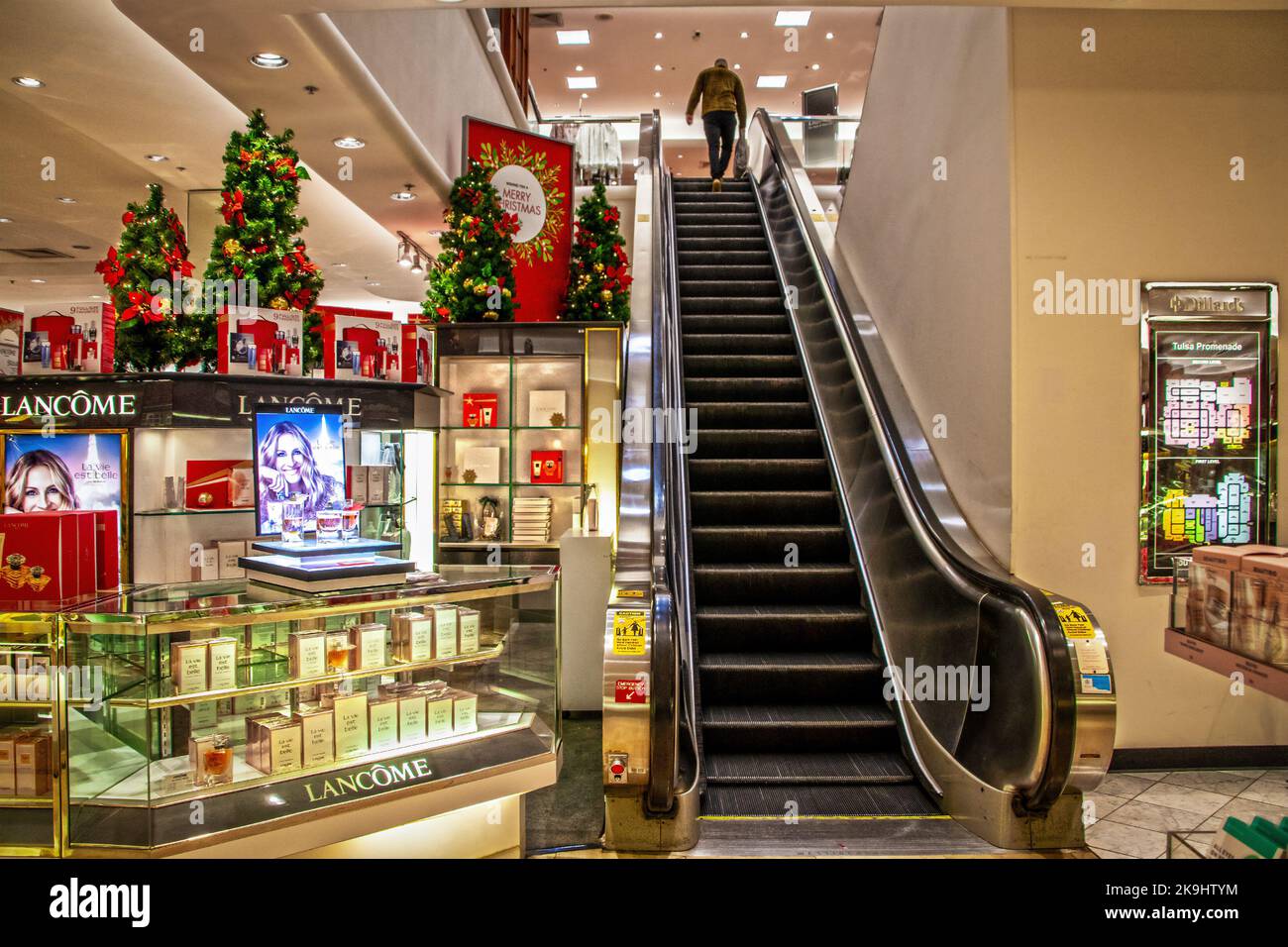 12-17-2021 Tulsa USA Kunde an der Oberseite der Rolltreppe im Kaufhaus zu Weihnachten mit Lancome Zähler auf einer Seite und Weihnachtsbäume schmücken sind Stockfoto