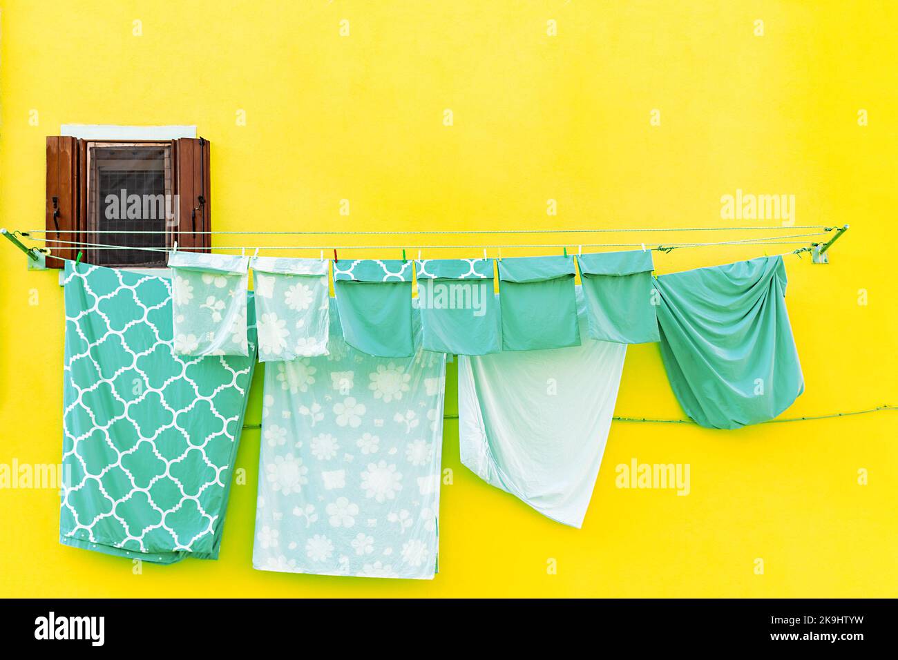 Die Wand mit dem Fenster und der Bettwäsche, die auf einer Linie auf der Insel Burano in Italien trocknet Stockfoto
