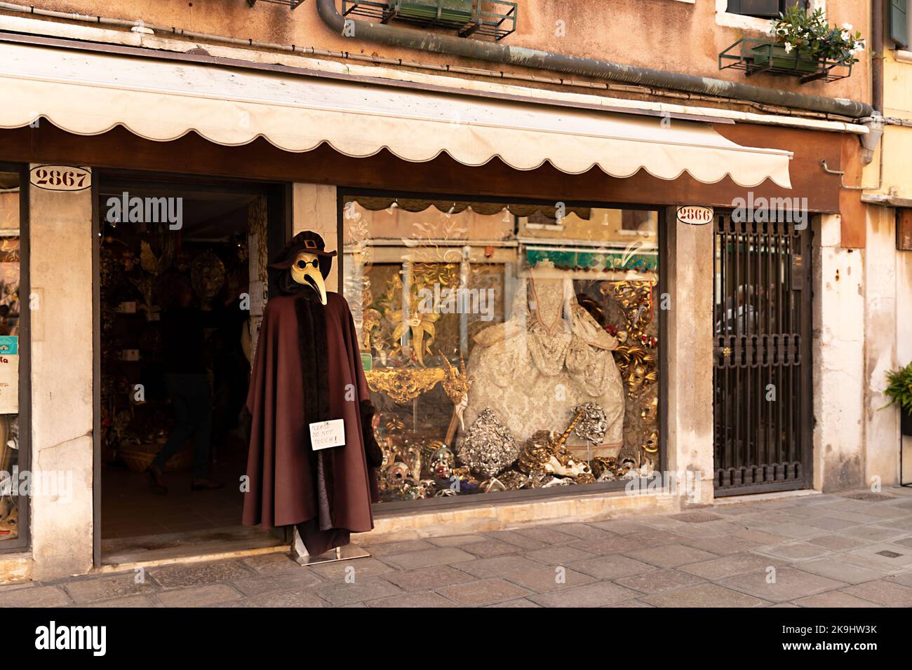 Der Laden in Venedig mit traditioneller venezianischer Kleidung für Karneval und Pestarzt-Kostüm auf der Vitrine Stockfoto