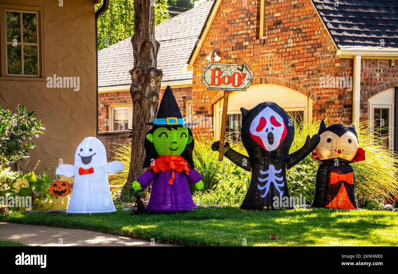 Halloween Dekorationen - Goblins und Spuk in der Nachbarschaft - niedliche Geisterhexe Skelett mit Buo-Zeichen und Vampir vor dem Haus Stockfoto
