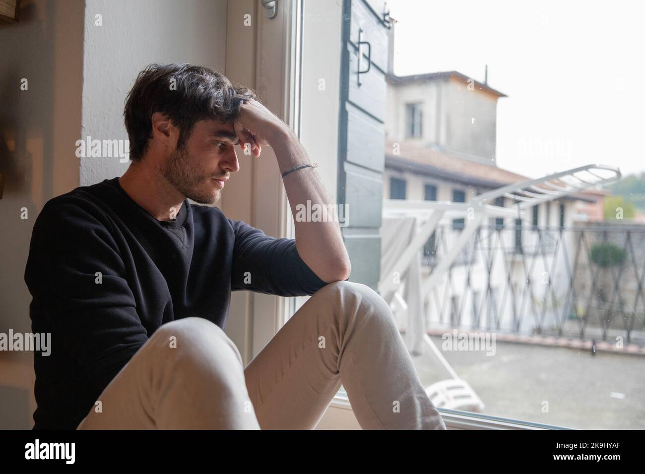 Einsamer, isolierter junger Mann, der auf dem Boden sitzt und meditiert. Depression-Konzept. Stockfoto