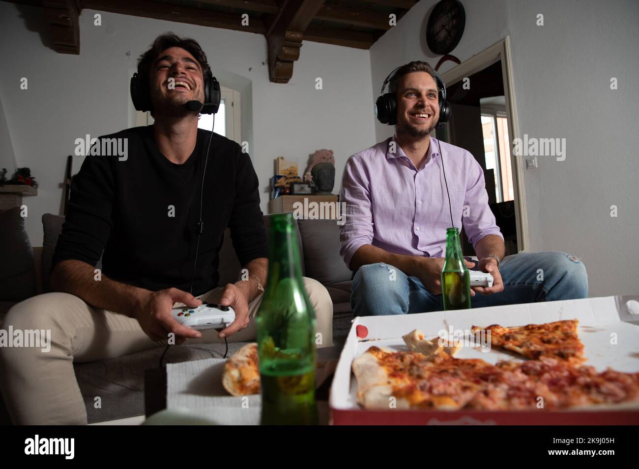 Freunde, die Spaß beim Spielen bei Videospielen haben, während sie Pizza essen und Bier trinken. Stockfoto