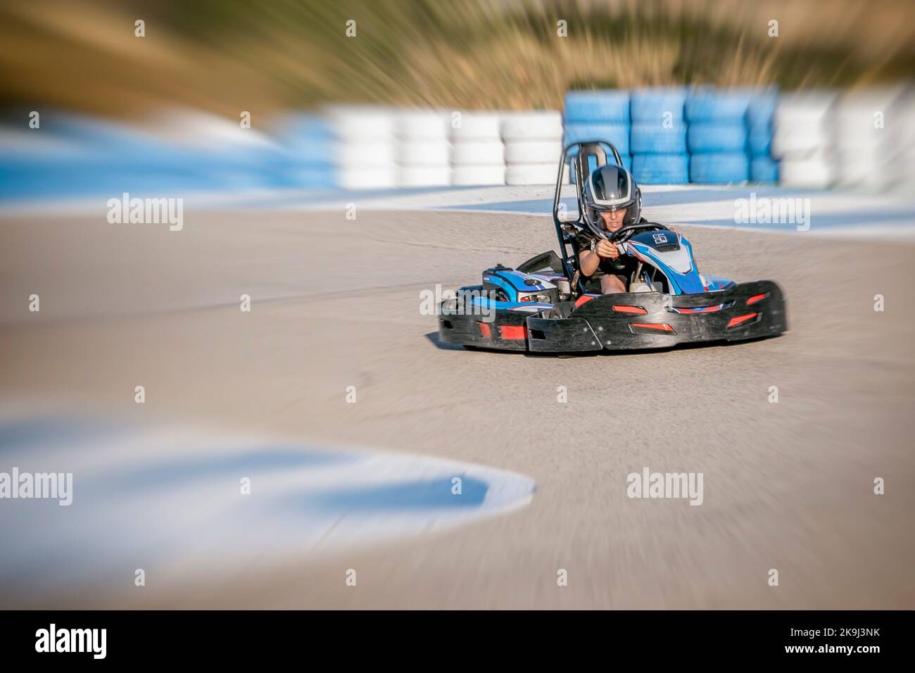Zoom-Effekt eines Teenagers, der einen Kart am Ausgang einer Kurve eines Kart-Rundgangs fährt, Gesicht der Geschwindigkeit und Konzentration, während er einen Kart fährt, defo Stockfoto