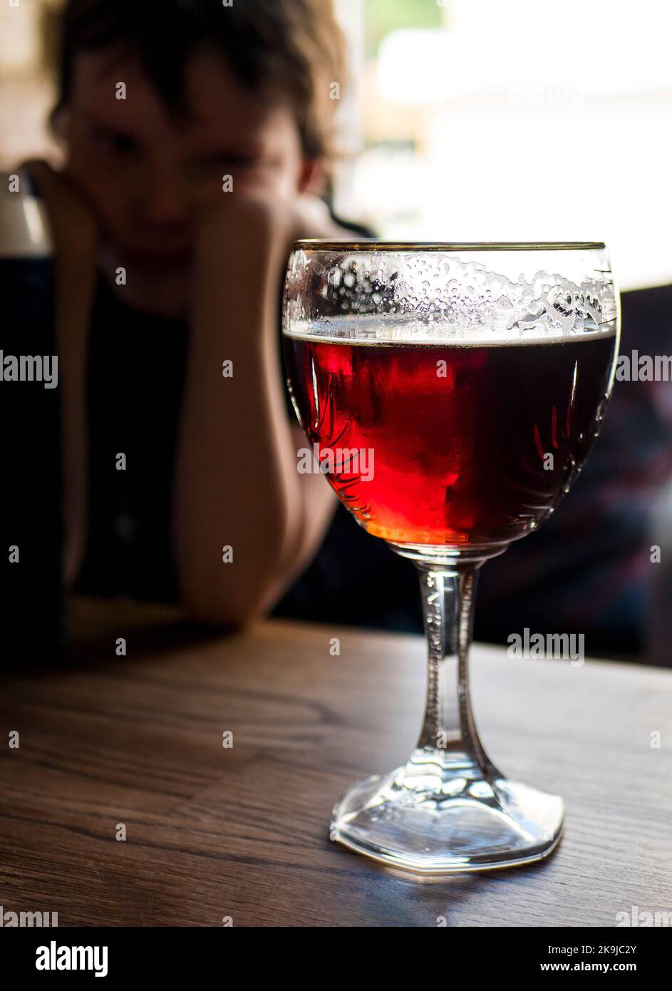 Bierglas und ein trauriges Kind auf dem Hintergrund, selektiver Fokus. Elterliche Probleme beim Trinken. Minderjährige Alkoholkonsum Stockfoto