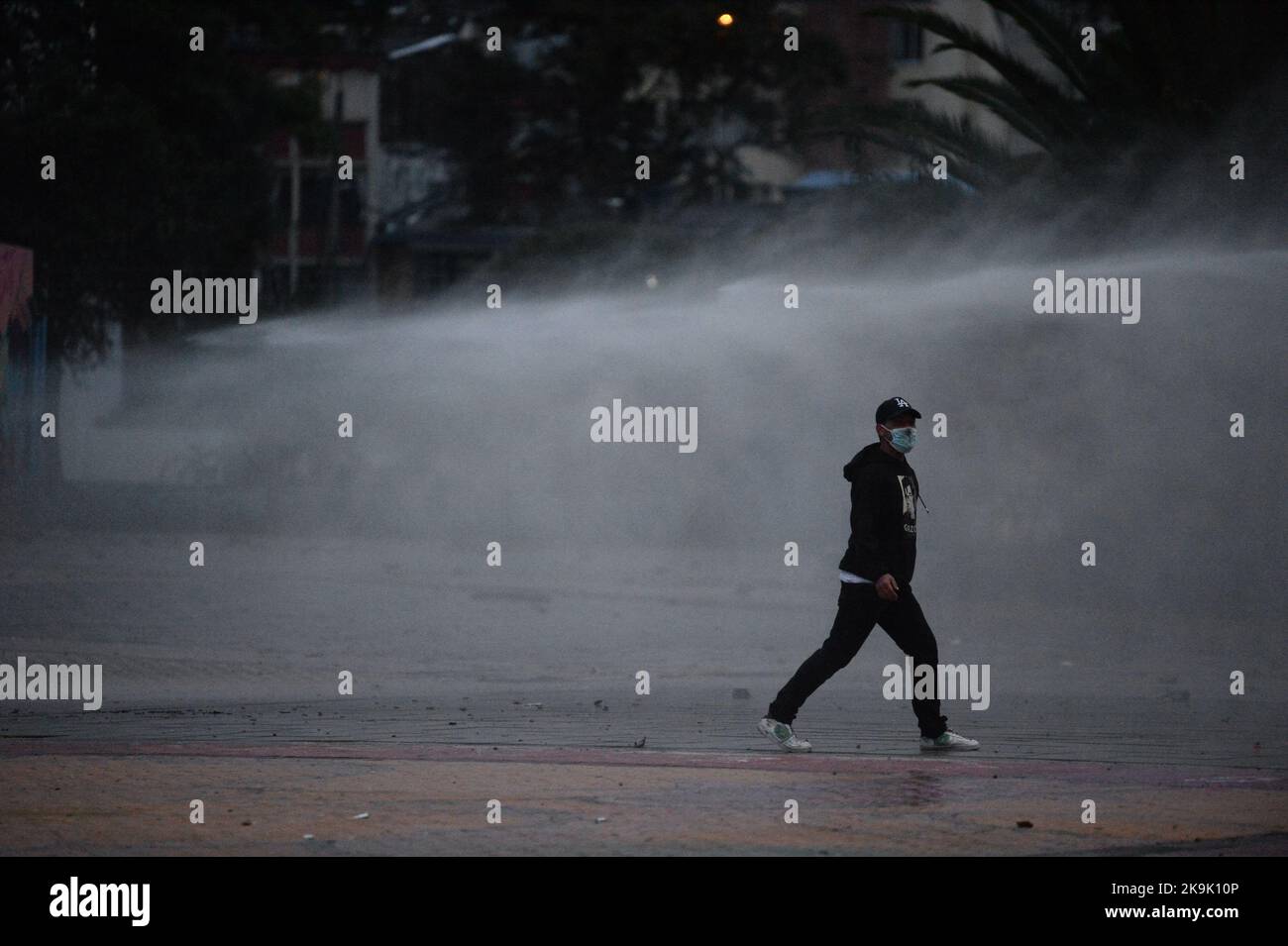 Ein Demonstrator steht während der Proteste in Bogota, Kolumbien, während die politischen Prisoners, die während der regierungsfeindlichen Proteste des letzten Jahres am 28. Oktober 2022 gefangen genommen wurden, befreit wurden, wie Wasser aus einem Wasserkanon-Aufstandsbehälter fällt. Foto: Lina Gasca Martin/Long Visual Press Stockfoto