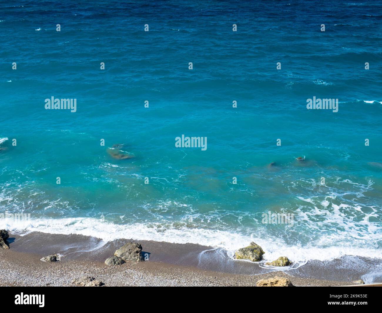 Schöner und einsamer Strand an der Westküste von Rhodos in der Nähe von Kamiros. Türkisfarbenes Meerwasser, blauer wolkenloser Himmel, Kiesstrand. Stockfoto