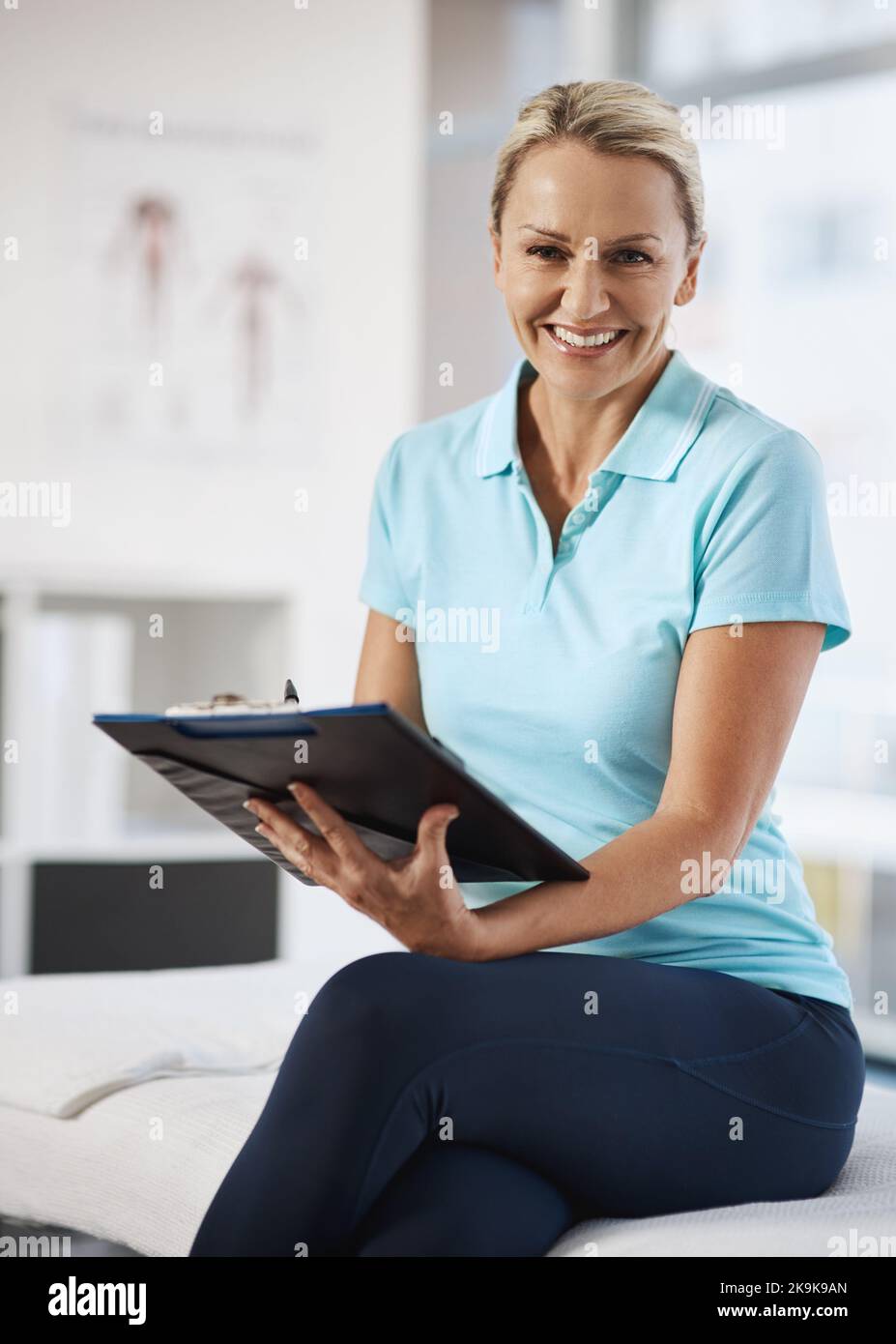 Ich behalte detaillierte Aufzeichnungen. Beschnittenes Porträt einer reifen Physiotherapeutin, die in ihrem Büro arbeitet. Stockfoto