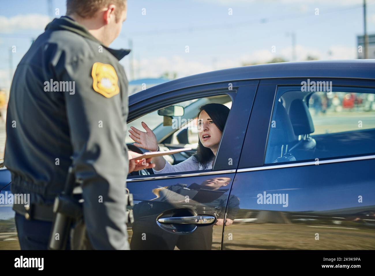 Bitte unterschreibt dies, Maam. Ein nicht erkennbarer männlicher Verkehrsbeamter, der an einer Straßensperre eine Fahrkarte an eine Zivilin ausstellt. Stockfoto