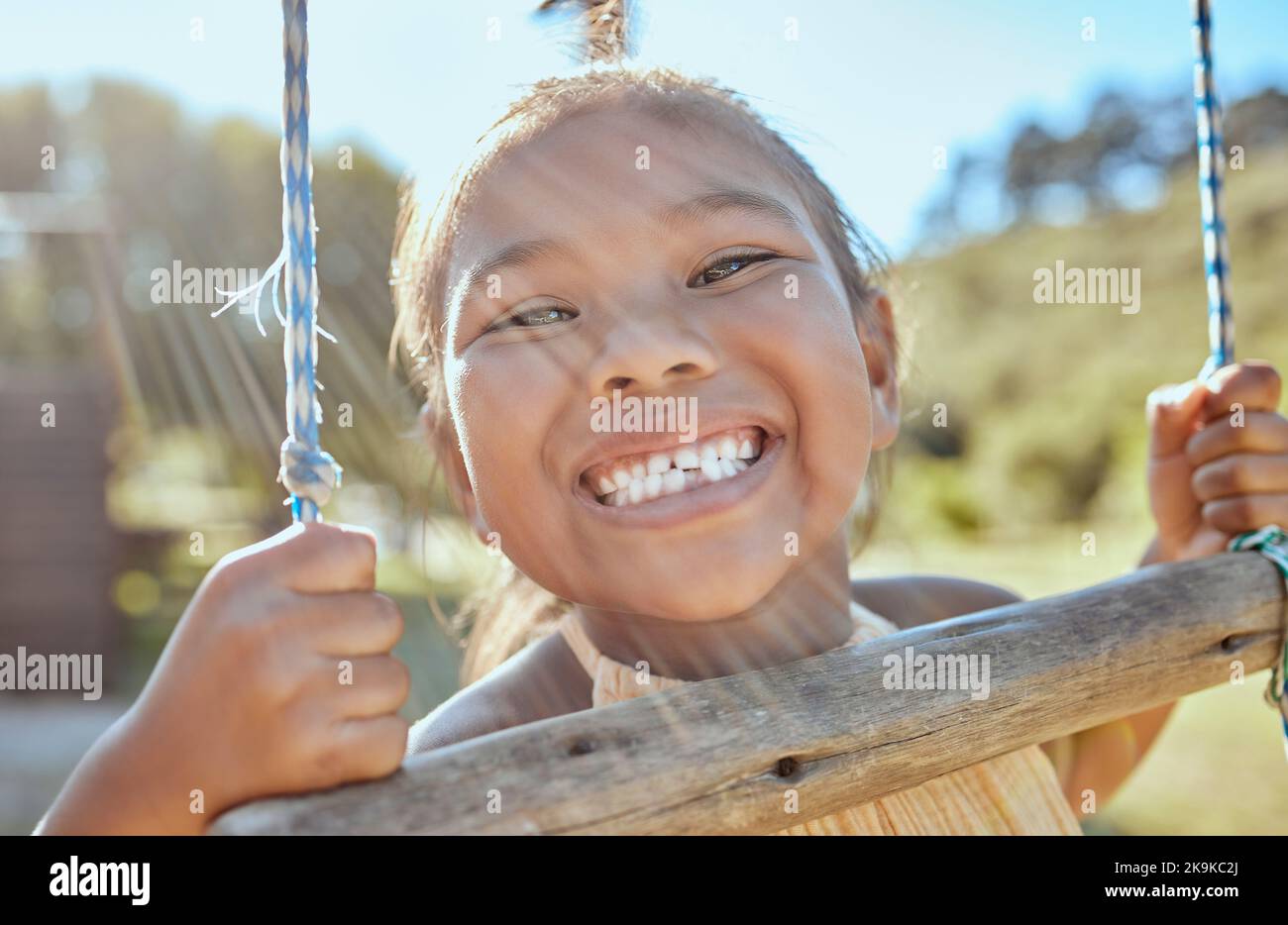 Lächeln, Zähne und kleine Mädchen auf Schaukel im Outdoor-Park, Glück Spaß und spielen draußen in Indonesien. Gesundheit, glückliches Gesicht und ein Porträt eines Jungen Stockfoto