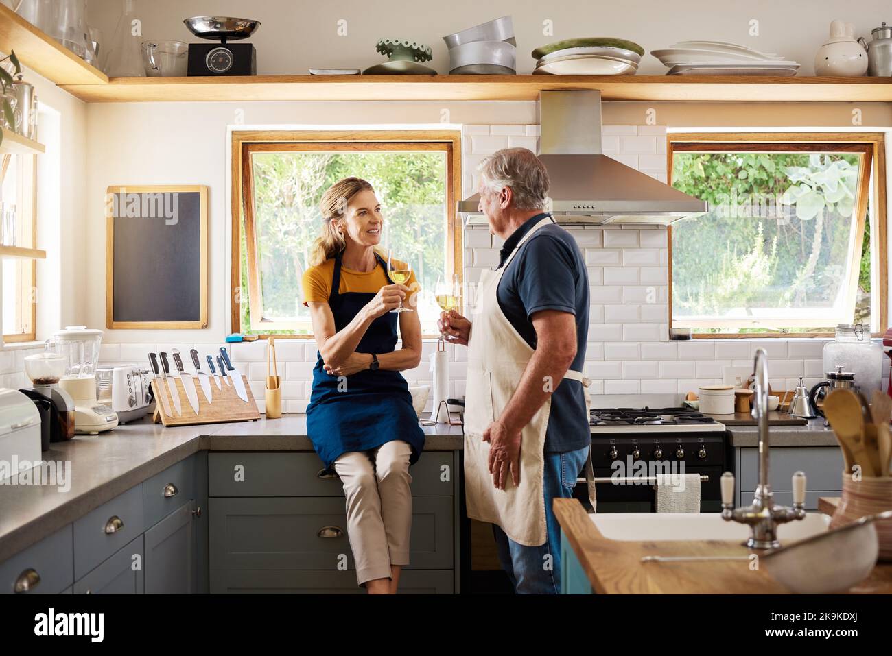 Liebe, Wein und reifes Paar in der Küche kochen, trinken und verbringen Freizeit zusammen zu Hause. Ruhestand, glücklicher Mann und Frau mit Weinglas Stockfoto