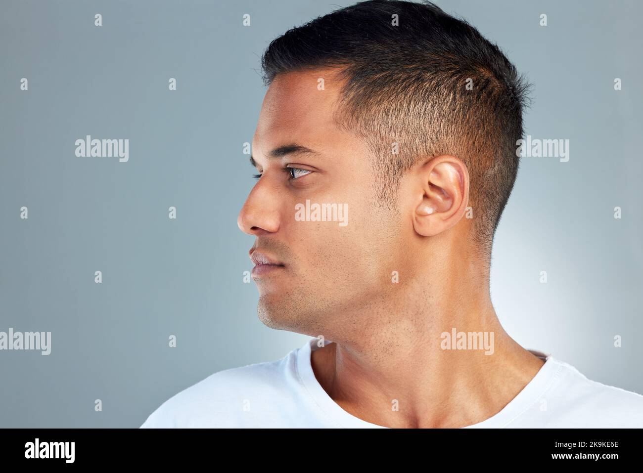 Gesicht, Schönheit und maskulin mit einem Mann-Modellprofil im Studio auf grauem Hintergrund für Hautpflege oder Wellness. Luxus, Gesundheit und Kosmetik mit einem Stockfoto