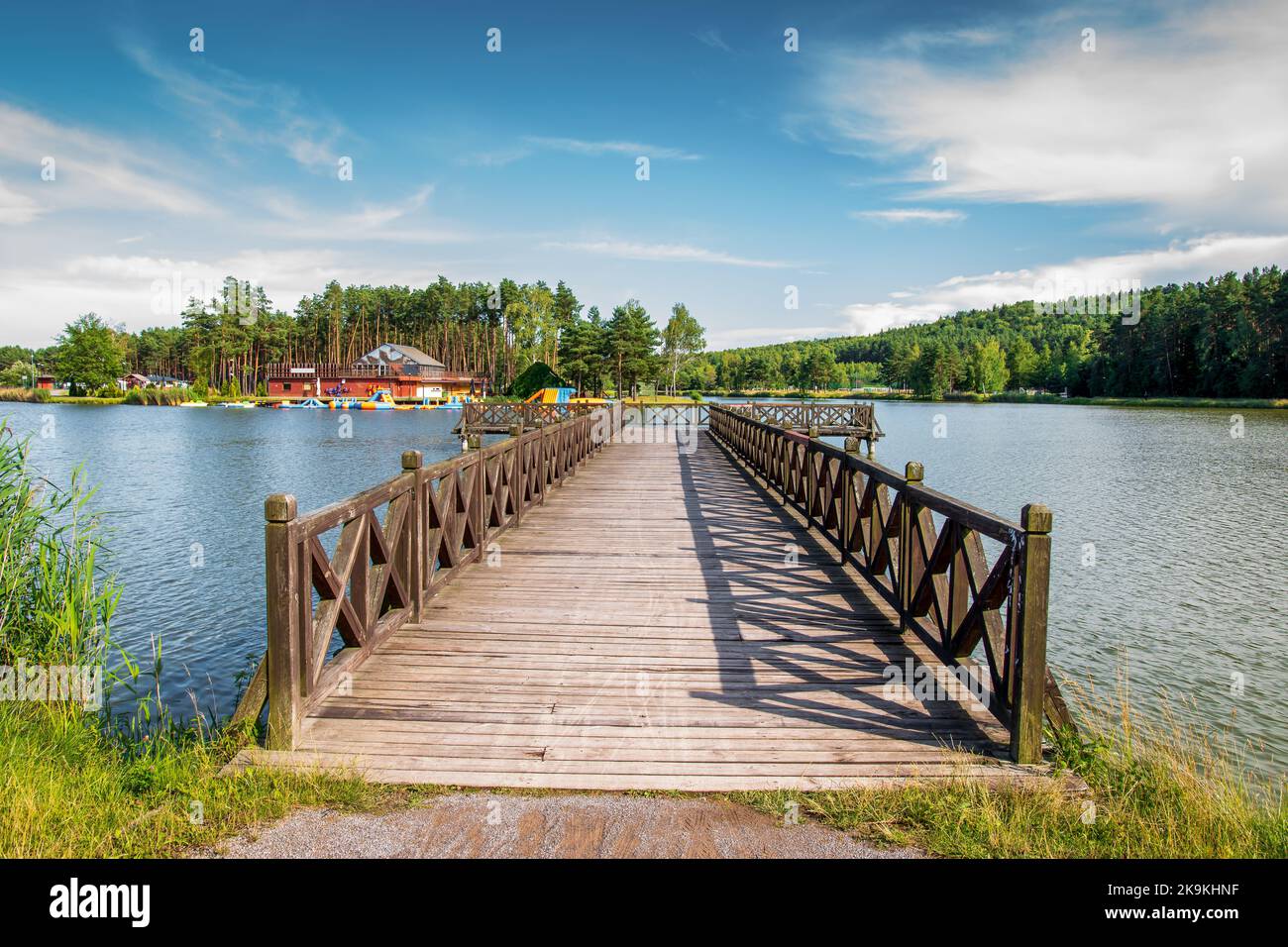 Ein wunderschöner hölzerner Pier über der Lagune. Die goldene Stunde an der Lagune, umgeben von Pinienwäldern. Krasnobród, Polen Stockfoto