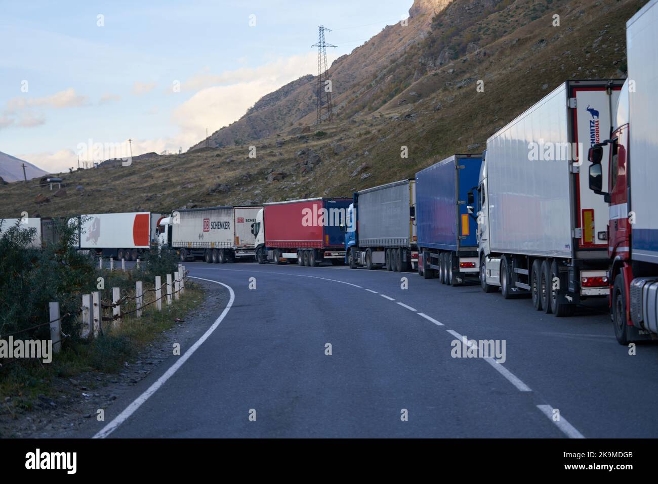 Kazbegi, Georgien - 2. Oktober 2022: Mehrere Kilometer lange LKW-Lkws an der Seite der georgischen Militärautobahn bei Kazbegi warten auf das Kreuz Stockfoto