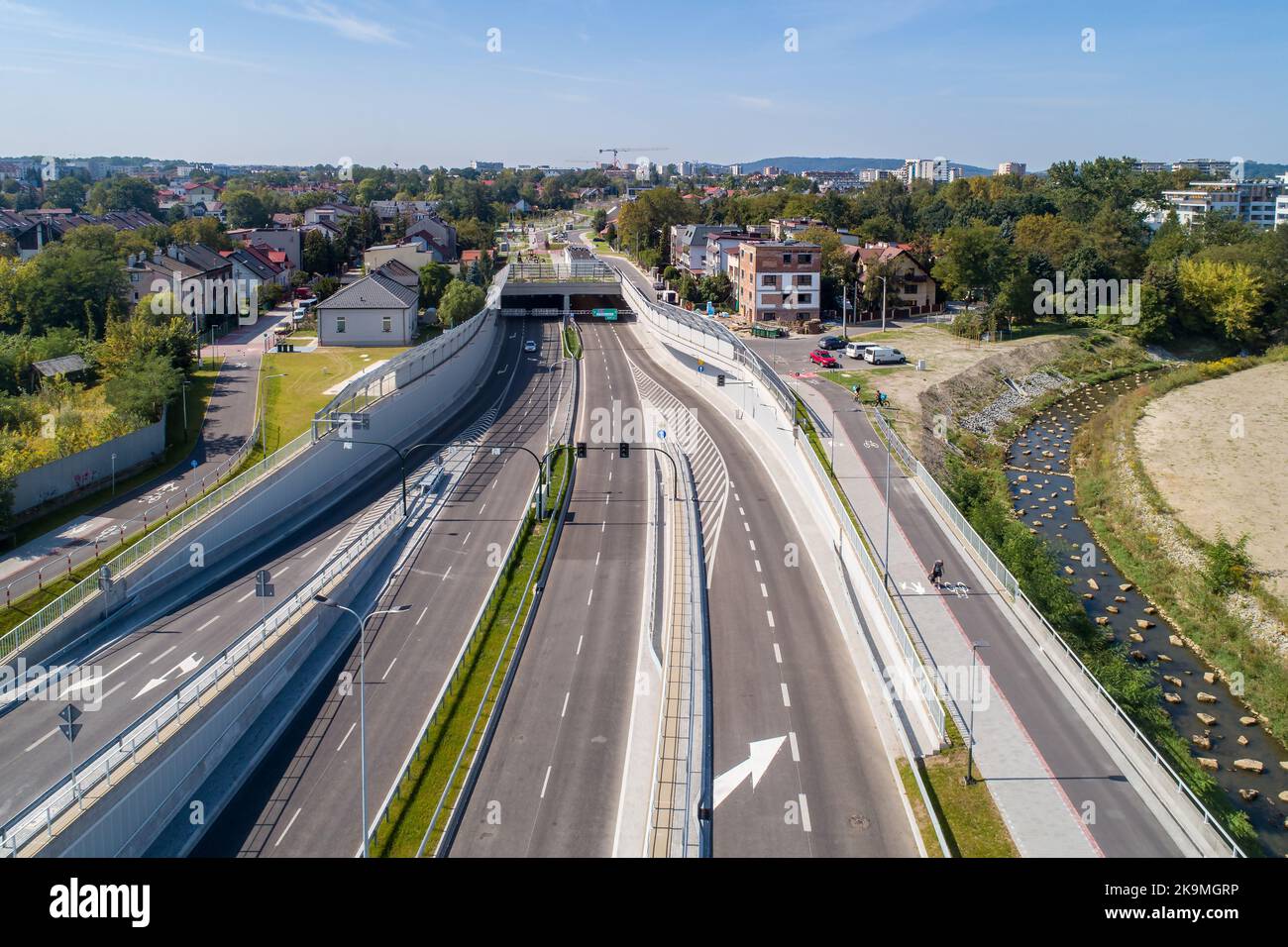 Neue Stadtautobahn Trasa Lagiewnicka in Krakau, Polen, mit Tunneln, Zufahrten, Radweg und Bürgersteig für Fußgänger. Regulierter Wilga-Fluss dekorieren Stockfoto
