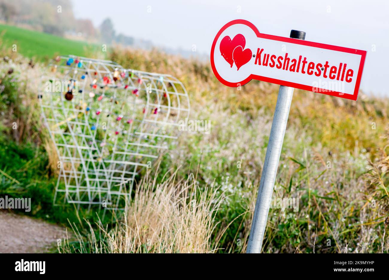 Wangerland, Deutschland. 29. Oktober 2022. Ein Schild mit der Aufschrift 'Kissing stop' steht in einem Feld neben einem Drahtgeflecht, das für sogenannte Liebesschlösser bestimmt ist. In der Nähe des Dorfes Bassens in der Gemeinde Wangerland können Liebhaber in diesem Rastplatz am Straßenrand für einen Kuss und gemeinsame Momente anhalten und sich mit einem von ihnen mitgebrachten Liebesschloss verewigen. Quelle: Hauke-Christian Dittrich/dpa/Alamy Live News Stockfoto