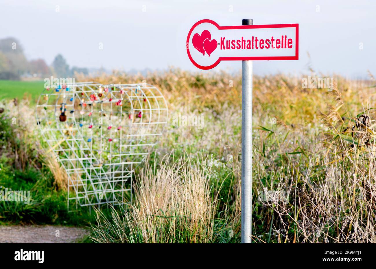 Wangerland, Deutschland. 29. Oktober 2022. Ein Schild mit der Aufschrift 'Kissing stop' steht in einem Feld neben einem Drahtgeflecht, das für sogenannte Liebesschlösser bestimmt ist. In der Nähe des Dorfes Bassens in der Gemeinde Wangerland können Liebhaber in diesem Rastplatz am Straßenrand für einen Kuss und gemeinsame Momente anhalten und sich mit einem von ihnen mitgebrachten Liebesschloss verewigen. Quelle: Hauke-Christian Dittrich/dpa/Alamy Live News Stockfoto