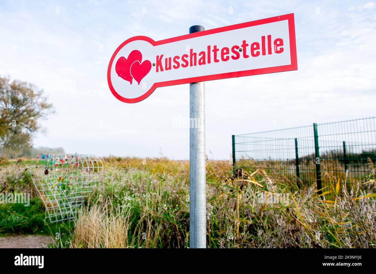 Wangerland, Deutschland. 29. Oktober 2022. Ein Schild mit der Aufschrift 'Kissing stop' steht in einem Feld neben einem Drahtgeflecht, das für sogenannte Liebesschlösser bestimmt ist. In der Nähe des Dorfes Bassens in der Gemeinde Wangerland können Liebhaber in diesem Rastplatz am Straßenrand für einen Kuss und gemeinsame Momente anhalten und sich mit einem von ihnen mitgebrachten Liebesschloss verewigen. Quelle: Hauke-Christian Dittrich/dpa/Alamy Live News Stockfoto