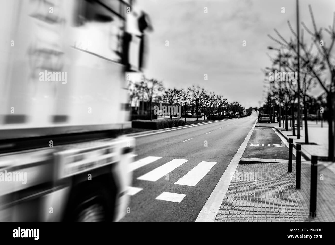 Verschwommener LKW im Vordergrund mit einer Straße vorne Stockfoto