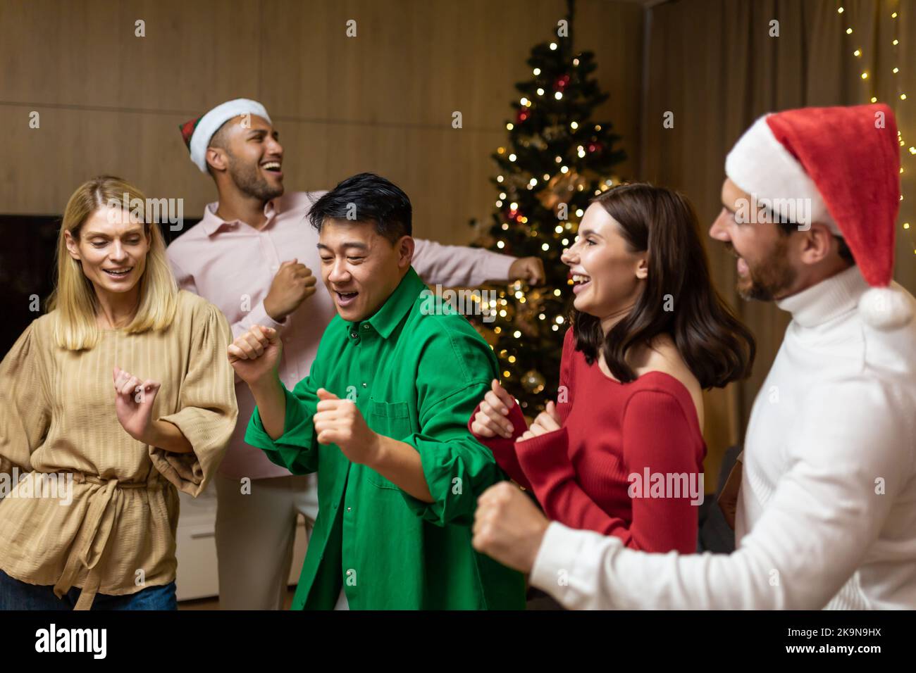 Fröhliche Gruppenfreunde feiern Silvester-Party zu Hause tanzen zusammen Heiligabend mit Spaß. Haus Silvester-Party. Verbringen Sie Zeit zusammen Feiertage Stimmung lustigen Mann und Frau. Stockfoto