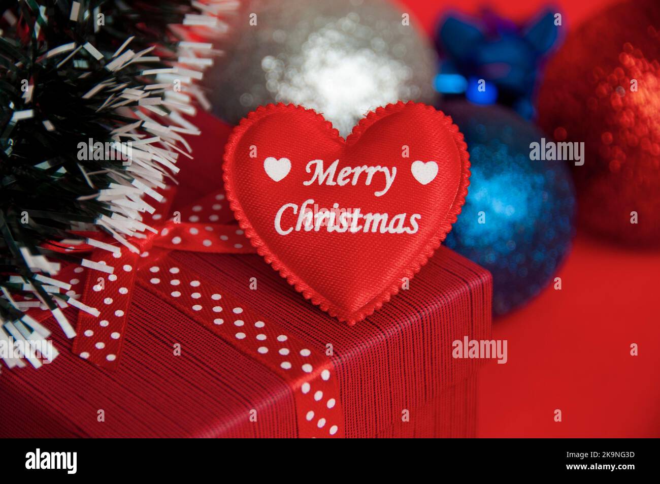Frohe Weihnachten Text auf Herz-Form auf der Oberseite der roten Farbe Geschenk mit Weihnachtsdekoration Hintergrund. Weihnachtsgeschenk und Copy Space Konzept. Stockfoto
