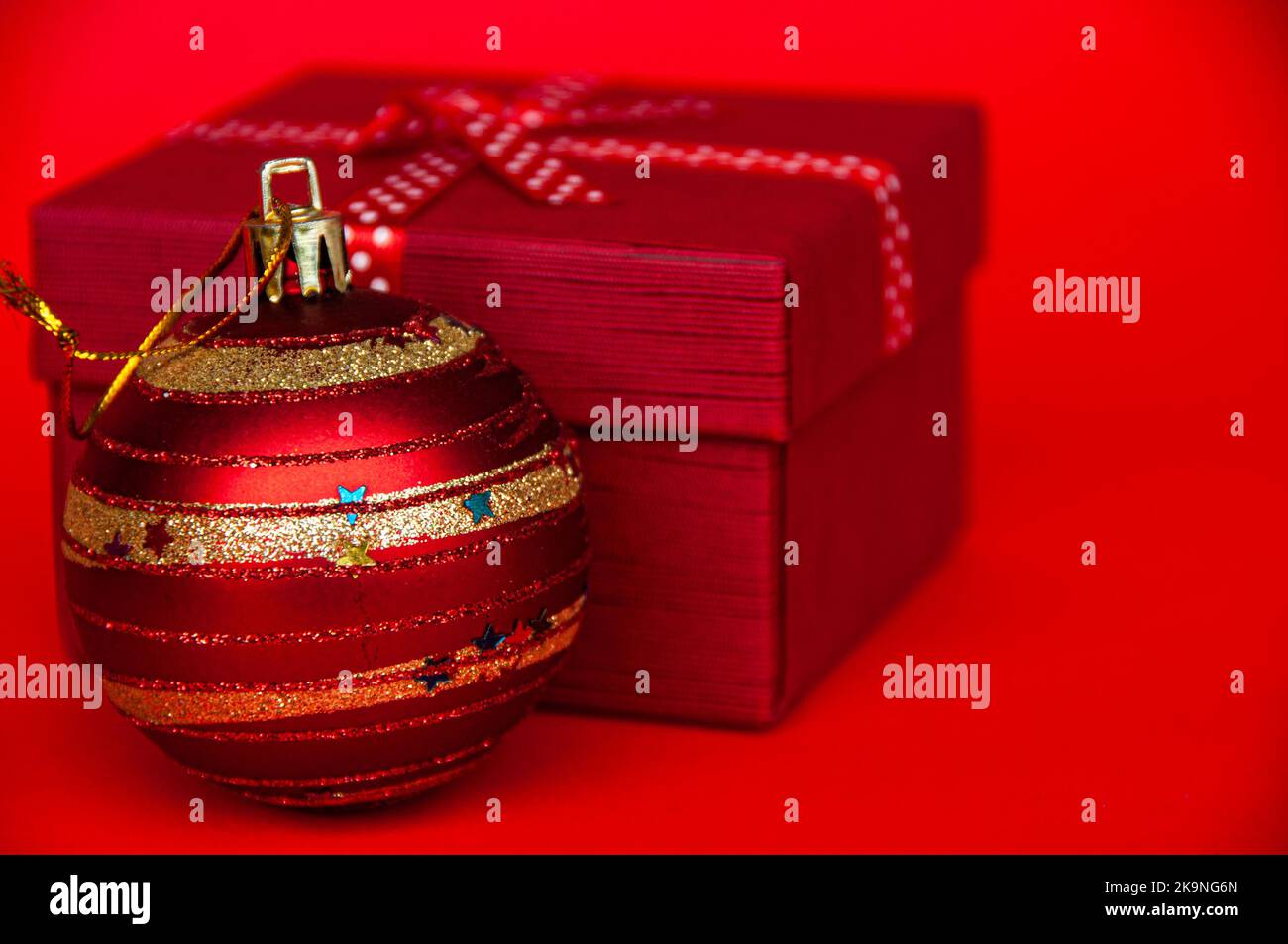 Geschenke und Weihnachtskugel auf rotem Cover Hintergrund. Weihnachtsfeier und Copy Space Konzept. Stockfoto