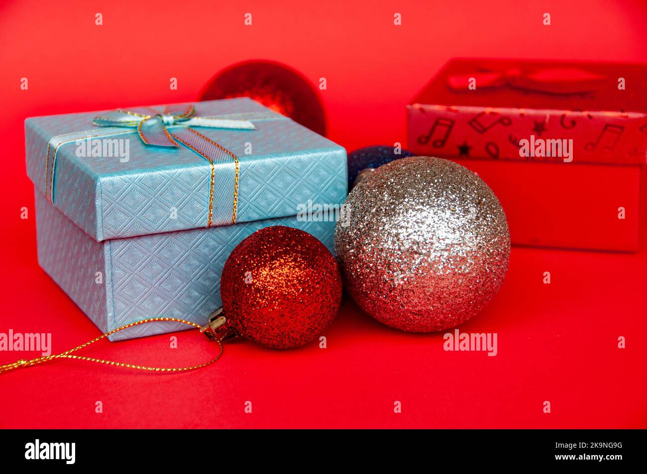 Geschenke und Weihnachtskugel auf rotem Cover Hintergrund. Weihnachtsgeschenk und Copy Space Konzept. Stockfoto