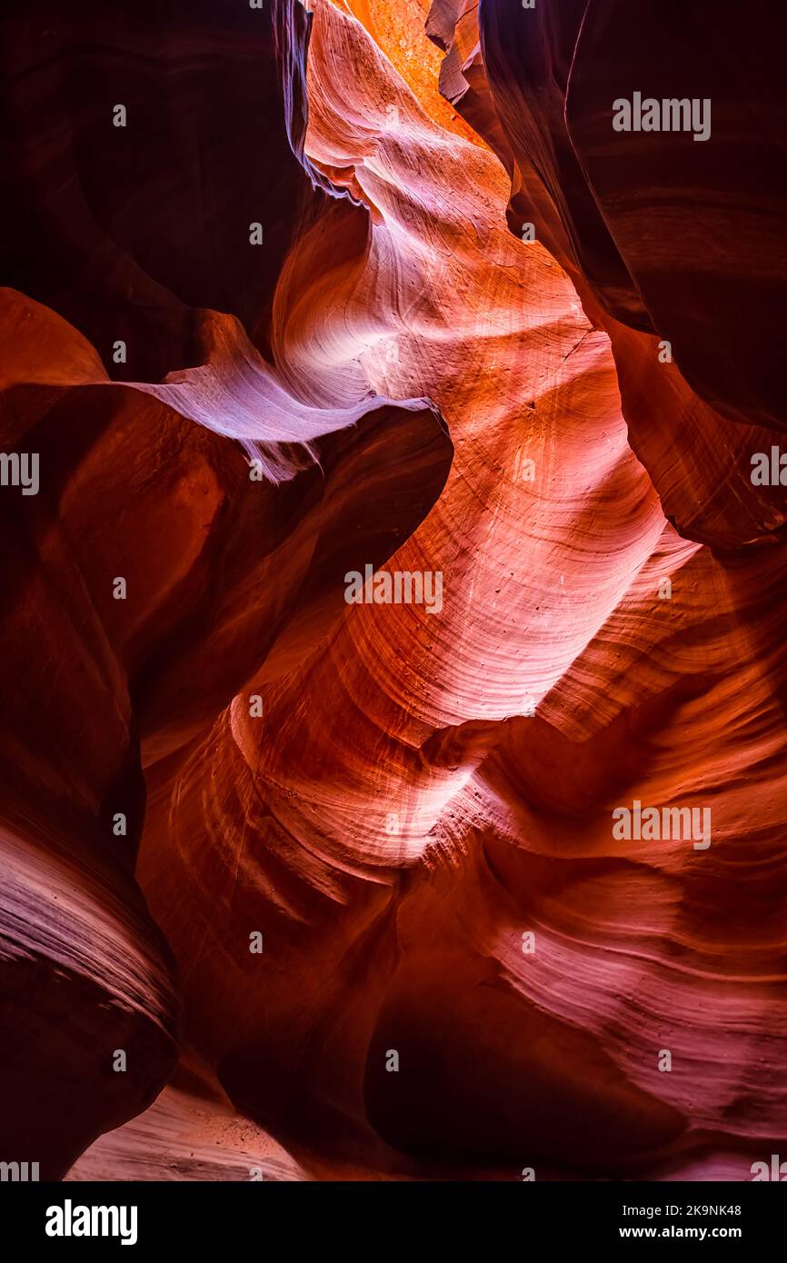 Vertikale Weitwinkelansicht von Schatten und Licht am oberen Antelope Slot Canyon mit wellenförmigen abstrakten Sandsteinfelsen aus rot-orangen Schichten Stockfoto