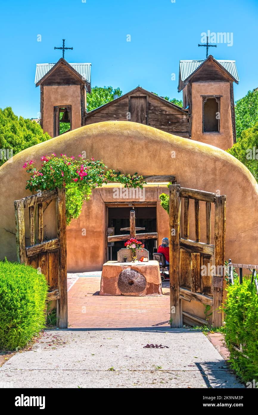 Berühmte historische Sanktuar-Kirche El Santuario de Chimayo in den Vereinigten Staaten mit Eingangstor durch Blumen im Sommer Stockfoto