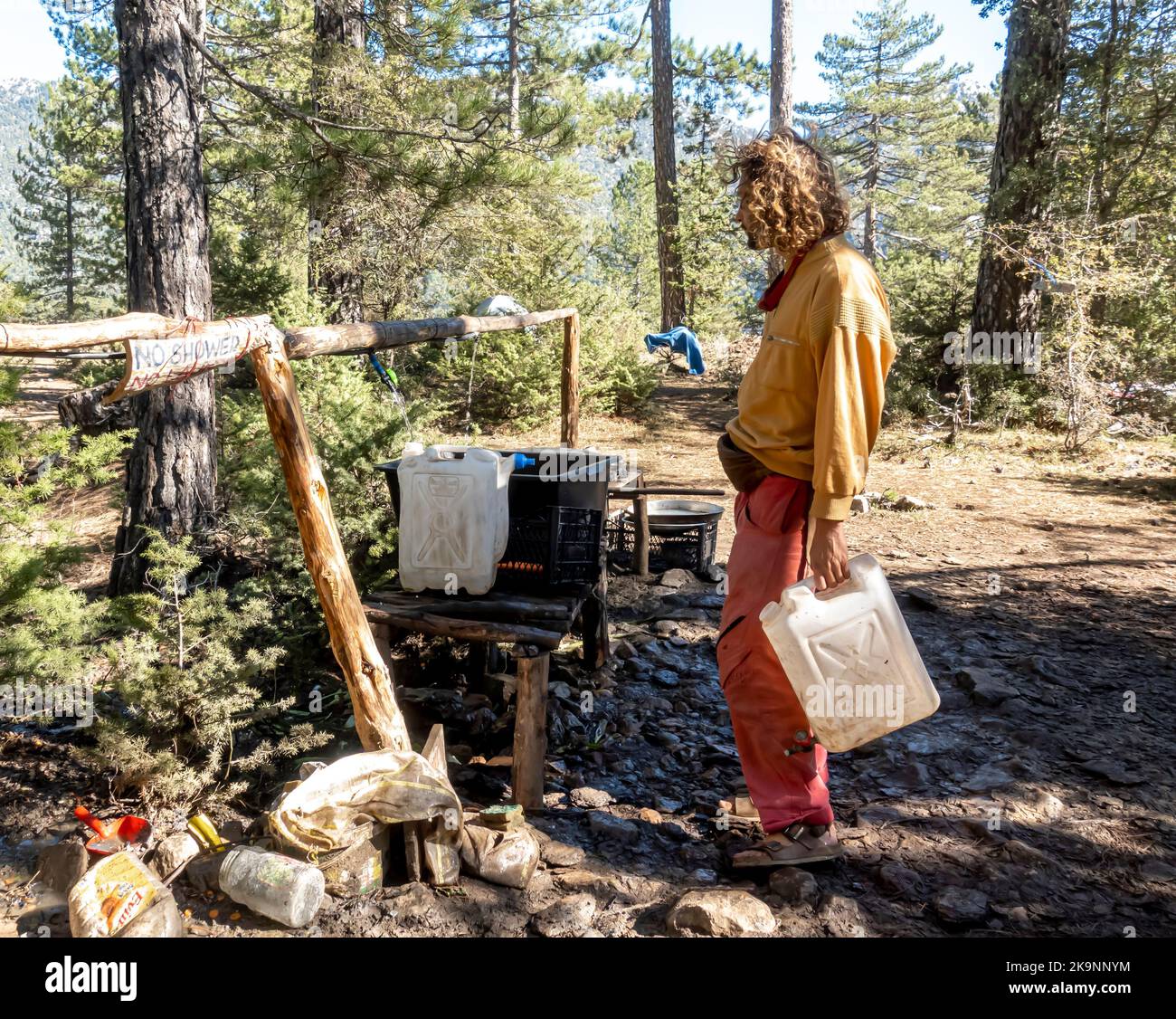 Familienmitglied, das das Wasser beim Rainbow World Gathering 2022 in Behälter füllte. Türkei. Stockfoto