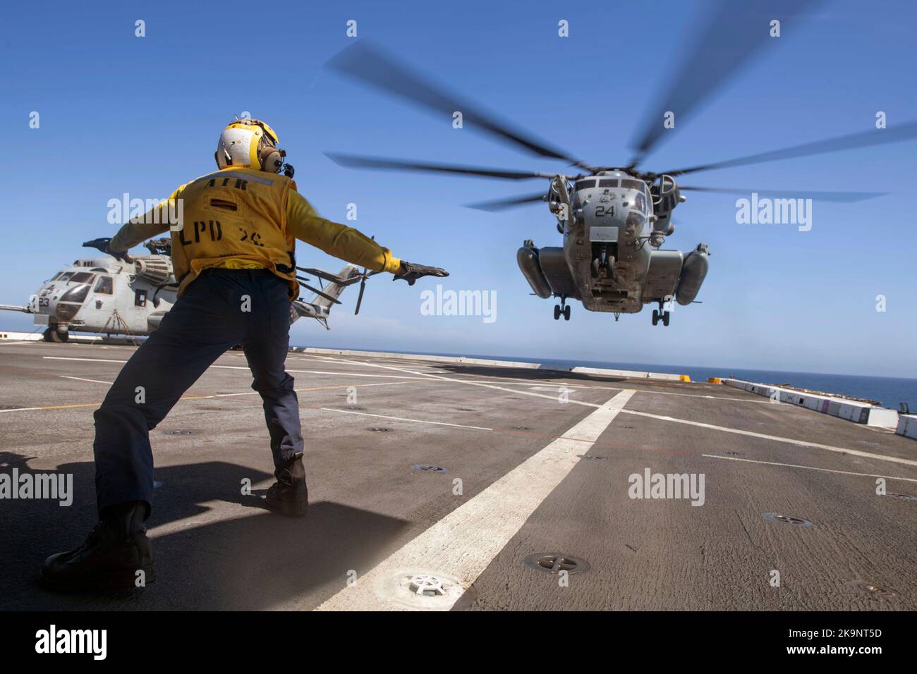Der Flugzeugführer Mate (Handling) von Aviation Boatswain leitet einen CH-53E Super-Hengst-Hubschrauber, der dem Marine Heavy Helicopter Squadron (HMH) 465 zugewiesen wurde, um auf dem Flugdeck des Amphibientransportschiffes USS John P. Murtha (LPD 26) zu landen. Stockfoto