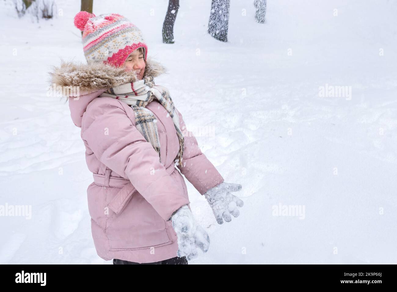 Glückliches kleines Mädchen spielt im Winterpark. Der Winterurlaub Stockfoto