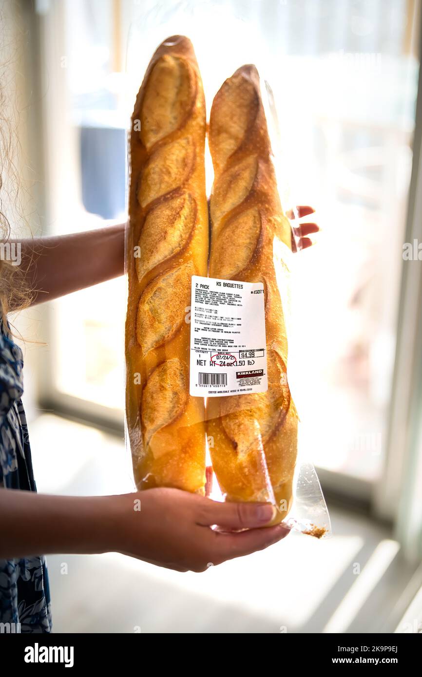 Hollywood, USA - 23. Juli 2021: Nahaufnahme einer weiblichen Person, die zwei frische französische Baguettes aus dem Costco Kirkland Signature Store in den Händen hält Stockfoto