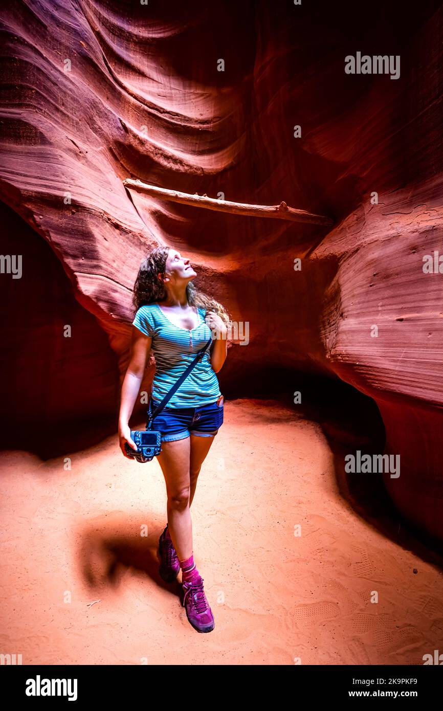 Junge Frau, die im Sommer in der Wüstenlandschaft des Upper Antelope Canyon mit Sandstein-Felsformationen steht Stockfoto