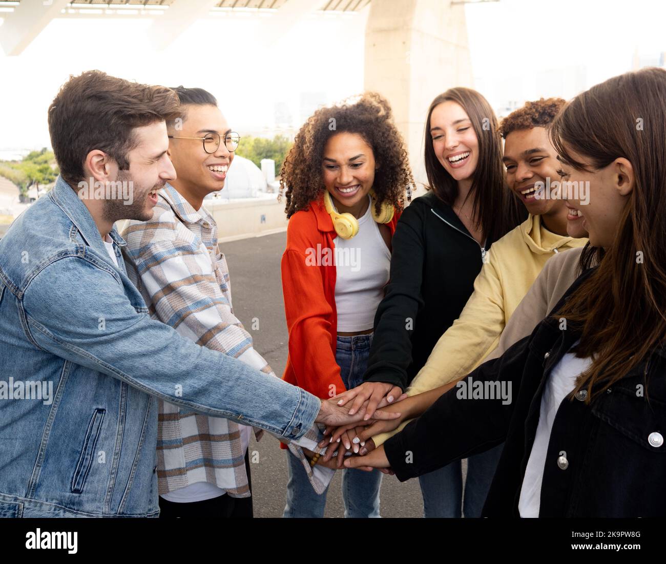 Eine Gruppe von multiethnischen jungen Freunden, die ihre Hände stapeln und feiern. Junge Millennials haben eine gute Zeit Stockfoto