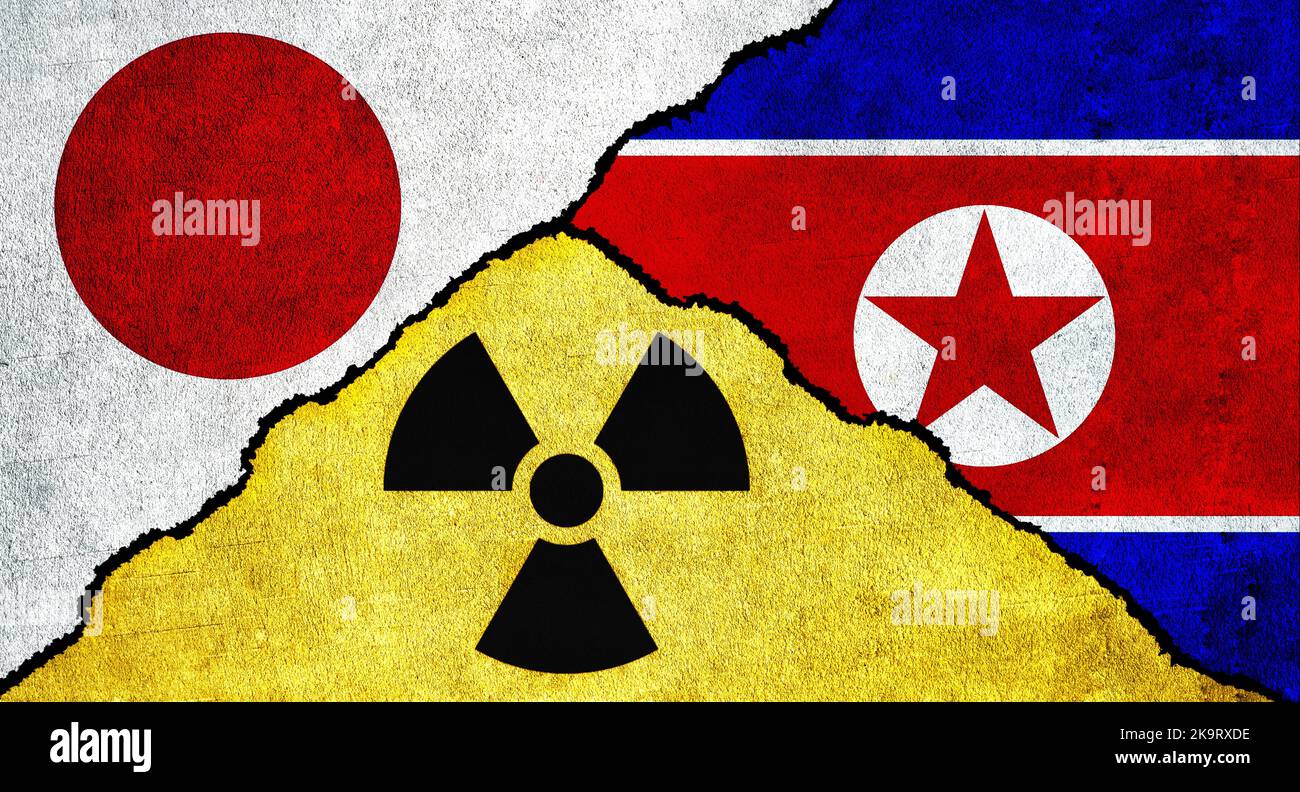 Flaggen von Japan, Nordkorea und Nuklearsymbol zusammen auf einer strukturierten Wand Stockfoto